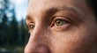 © David - Close up of a woman's hazel eyes showing natural freckled skin texture and detailed eyelashes while looking away in soft outdoor light