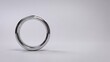 © IMAGINATION STUDIO - Polished metallic ring standing upright isolated against soft minimalist neutral gray studio background surface texture