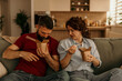 © La Famiglia - Couple enjoying take-out food on sofa at home