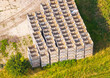 © Amazing Aerial - Aerial view of stacked wooden crates arranged in a large grid on a grassy field in Choczewo, Pomeranian Voivodeship, Poland.