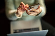 © Davor - Person using smartphone while working on laptop at home