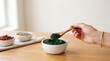 © sabrang - Person scooping green spirulina powder with wooden spoon from bowl