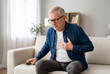 © Meow Creations - Senior man with chest pain reaching for a phone on a sofa