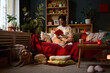 © DragonImages - Young adult African American woman sitting on sofa and reading book with dog lying on floor. Image represents mental wellbeing and leisure, suitable for lifestyle marketing campaigns