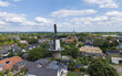 © Amazing Aerial - Aerial view of Molen Op Hoop van Beter windmill surrounded by traditional houses, a church, and lush greenery in Ingen, Gelderland, Netherlands.