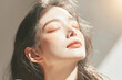 © ROni051 - Close-up portrait of beautiful East Asian woman tilting head back with closed eyes under warm dramatic sunlight for skincare, facial care, cosmetics, and wellness concept