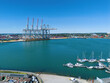 © Amazing Aerial - Aerial view of Southampton Port featuring large container cranes, rows of shipping containers, and a marina with various boats docked in Southampton, United Kingdom.