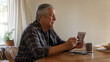 © AlenaSi - Elderly man reflecting on memories while holding a photograph at wooden table. Emotional moment illustrates connection to past, showcasing feelings of nostalgia and loss.