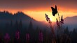 © pupus - Silhouette of butterfly perched upon blooming wildflowers against a vibrant mountainous sunset