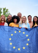 © CarlosBarquero - Vertical. Multiracial group of friends holding the European Union flag with pride, symbolizing unity and diversity. Joyful atmosphere outdoors, promoting togetherness and cultural vibrant harmony