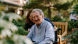 © Tania - soft focus plant leaf bokeh surrounding elderly man in memory care garden during World Alzheimers Day outdoor activity program with caregiver kneeling at his level in wide