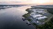 © Iryna - High Dawn Aerial of a White Data Center Campus on a Wooded Headland Beside a Broad Mist Covered Reservoir With Silver Intake Pipework Running Down to the Shoreline Technology