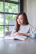 © Farknot Architect - Vertical portrait image of a woman reading a book with coffee cup on the table