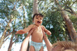 © MexChriss - Happy baby playing in arms outdoor among trees