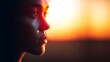 © Tanakrit - Close-up side profile of a person with a tear on their cheek, illuminated by warm, soft light against a blurred orange background.