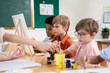 © Kawee - Diverse students coloring on painting board on table at elementary school.