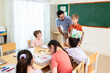 © Kawee - Caucasian schoolboy presenting drawing artwork to classmates in classroom.