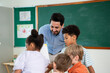 © Kawee - Caucasian male teacher teaching art lesson to children in classroom.