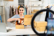 © Kawee - Caucasian woman live streaming and selling clothes in fashion store.