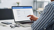 © Sumi - Employee pointing at a medical leave request form on a laptop screen while working at a modern office desk with glasses and smartphone
