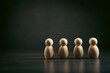 © Artvibe - Wooden figures of people stand in a row on a black background