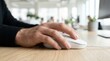 © Ronnayut - A man's hand using a computer mouse on a wooden desk in an office setting, closeup view.