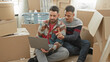 © Krakenimages.com - Man and partner sit on floor holding laptop while partner rests hand on his knee among moving boxes in building; moving day togetherness.