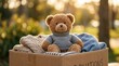 © Ronnayut - A childhood charity and giving concept featuring a teddy bear in a clothes donation box under warm sunlight