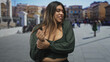 © Krakenimages.com - Woman holding wrist near exposed cleavage, grimacing and pulling sleeve while standing in a crowded pedestrian street with blurred buildings and passersby; discomfort.