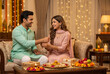 © Stockphotosbysumit - Raksha Bandhan celebration with sister tying rakhi to brother at home.