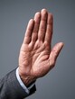 © Kreation - Male hand in a suit making a palm-up gesture on a gray background symbolizing request or bankruptcy.