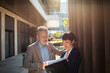 © Davor - Two business colleagues reviewing documents outside office building