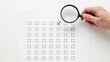 © Nadia - Hand holding a magnifying glass inspecting a check sheet with one correct box checked out of many
