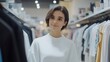 © Tara - Young Woman Browsing Clothes in a Department Store.
