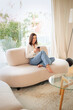 © gzorgz - Attractive brown haired woman texting on her mobile phone while sitting on a modern couch