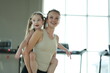 © ultramansk - Loving mom and her cute child carry the girl on her back laughing in the gym sharing a tender moment in a bright sunlit gym, candid real moment. Healthy active lifestyle of a modern family