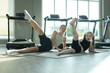 © ultramansk - Sporty young woman and her girl in black leggings lift single legs skyward in side lying position on a mat in a bright gym with large windows. Real people enjoying everyday life moments