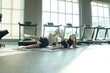 © ultramansk - Sporty young woman and her girl in black leggings do synchronized side leg lifts on the mat at their morning exercise session in the gym, shallow depth of field