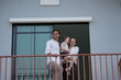 © ultramansk - Happy young family with little daughter greet the neighborhood from the balcony with their daughter on the upper balcony of their new home above the neighborhood, shallow depth of field