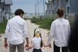 © ultramansk - Cheerful Caucasian family of three stroll along the unpaved street of the new development holding hands among modern new houses of a suburban housing estate, candid real moment