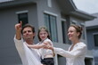 © ultramansk - Young couple with their laughing daughter celebrate as the girl jumps and dad scoops her up among modern new houses of a suburban housing estate, authentic everyday scene
