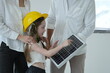 © ultramansk - Happy young family with little daughter in a toy hard hat guide their daughter's hand across the solar module surface inside their new energy efficient home, candid real moment