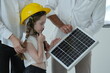 © ultramansk - Young parents teaching their curious child let the girl in a toy helmet touch the photovoltaic cells up close in their future eco friendly house in warm natural light