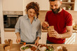 © La Famiglia - Couple enjoying takeaway meal with chopsticks in kitchen