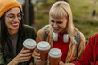 © La Famiglia - Friends toasting coffee cups outdoors and laughing together