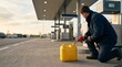 © SashaMagic - Man filling a yellow jerrycan with gas at a station, low angle shot with copy space