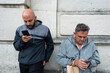 © Nazareno - Men browsing smartphones focusing on screen against wall
