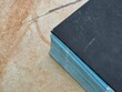 © Hendra Susanto0311 - Close up corner view of thick black hardcover notebook with blue paper edges on tile background