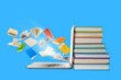 © Atlas - Books are stacked beside a laptop with pages flying up