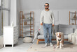 © Pixel-Shot - Blind young man with stick and guide dog at home